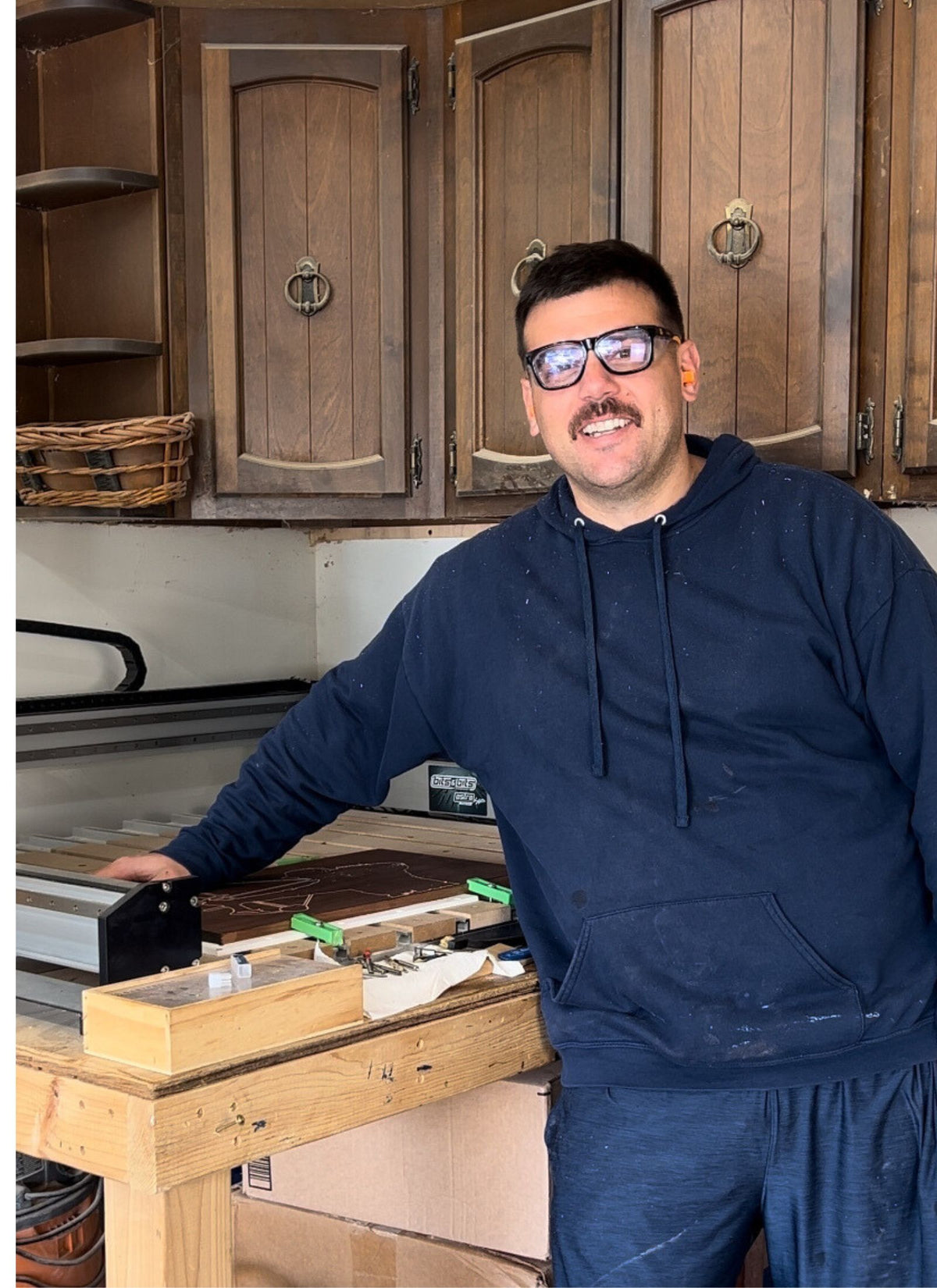 Justin beside his CNC router in his woodworking workshop